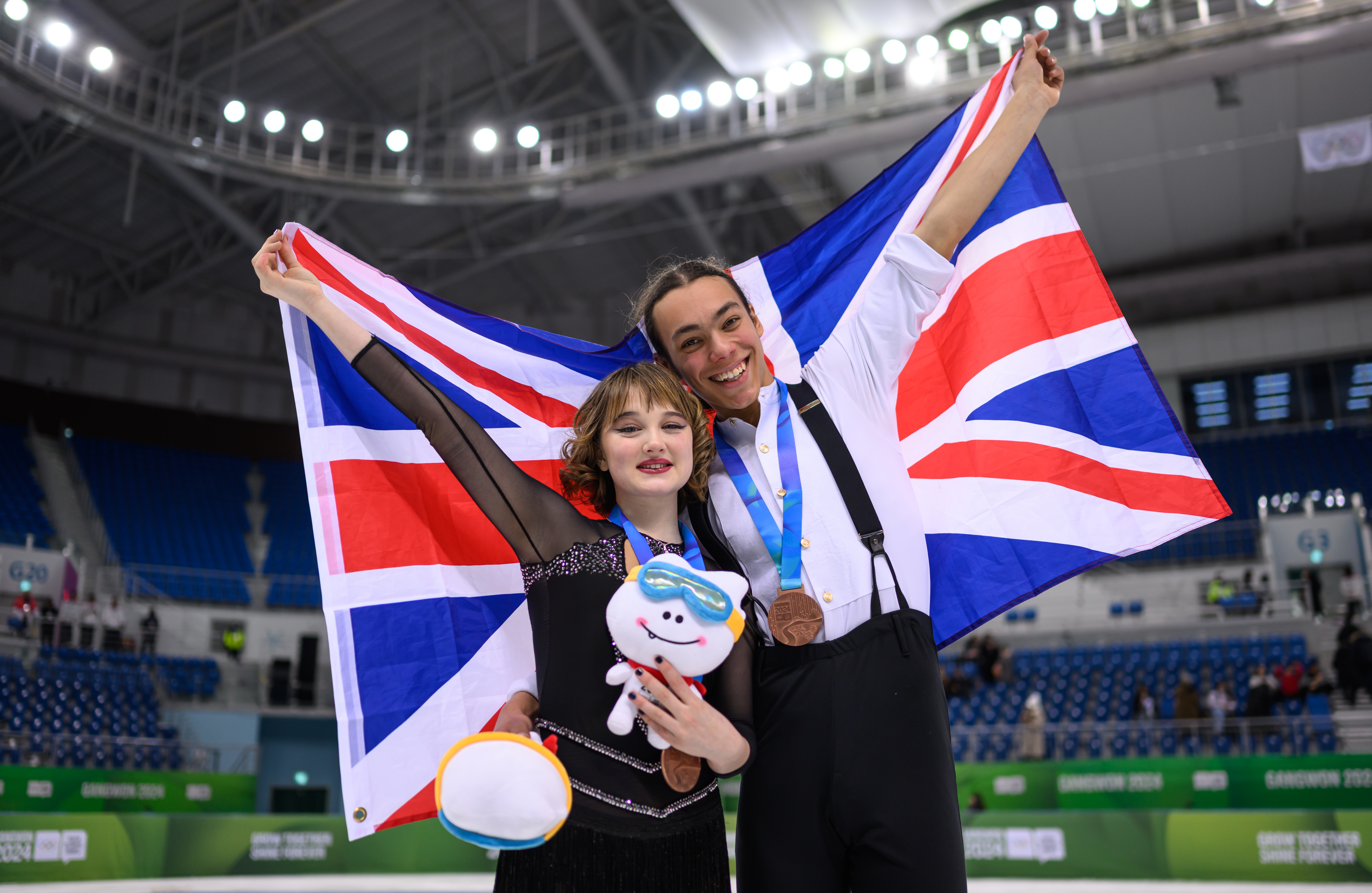 Bronze medalists Ashlie Slatter (GBR) and Atl Ongay Perez (GBR) on the ice with their national flag after the medal ceremony for the Ice Dance